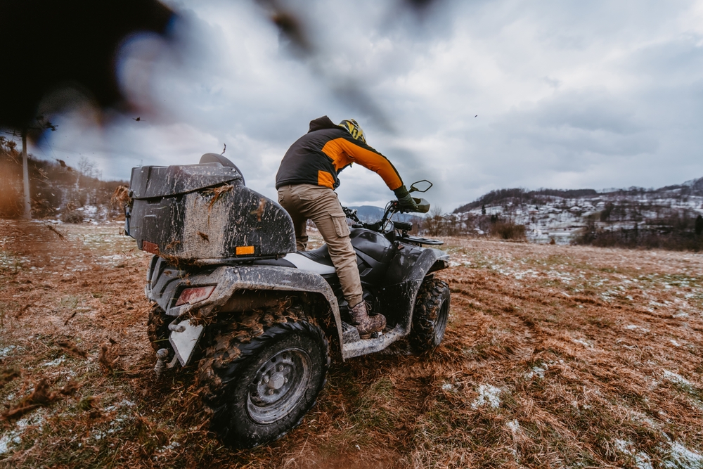 Bărbat care conduce un ATV pe un teren înghețat